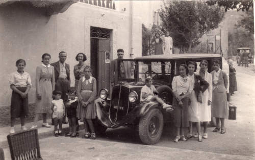 Foto risalente di quasi 100 anni fa, rappresentante una macchina d'epoca con disposti tutto attorno diverse persone.